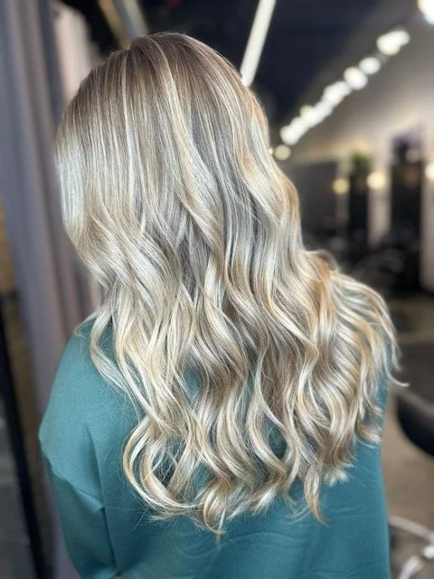Bright blonde balayage with soft, voluminous waves and seamless root blend, created at Chroma Salon Seattle using professional Aveda blonding techniques.