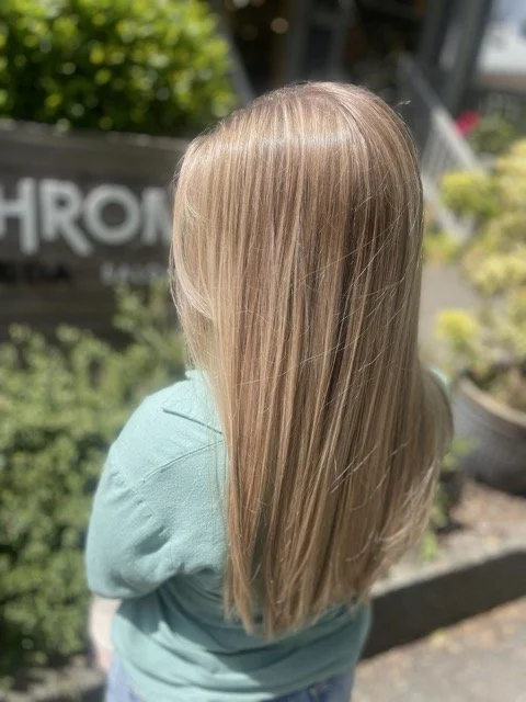Smooth, sun-kissed blonde Aveda hair color with glossy finish, styled at Chroma Salon Seattle for healthy, radiant shine.