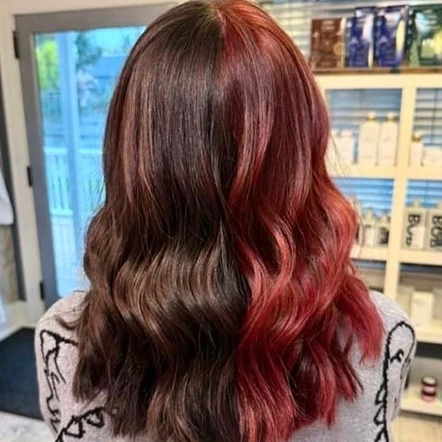 Split-dye brunette and red hair with soft waves and shoulder-length layers, created by Stormi at Chroma Salon Queen Anne Seattle for bold, high-contrast color.