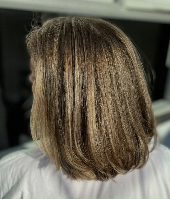 Soft golden brunette bob with dimensional highlights and a smooth, glossy finish created with Aveda color at Chroma Salon Seattle.