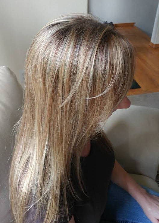 Dimensional beige blonde highlights blended through a soft golden blonde base for natural-looking brightness and depth. This long layered haircut features face-framing movement, seamless color transitions, and a smooth, healthy-looking finish that en