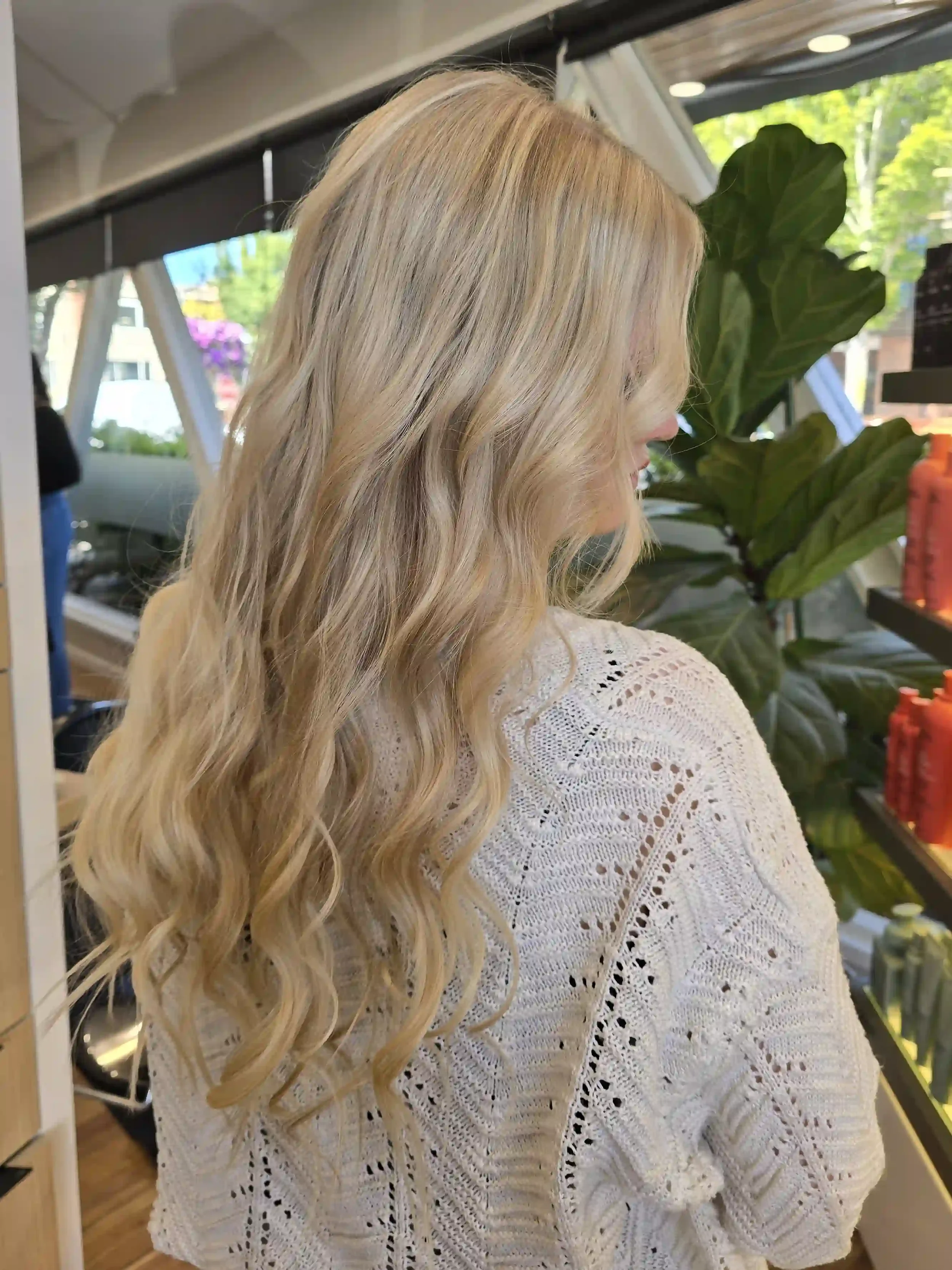 Long platinum blonde balayage with a soft shadow root, bright icy ribbons, and flowing Hollywood-inspired waves. This dimensional blonde color delivers maximum brightness with a seamless blend for a luxurious, low-maintenance finish full of shine, so