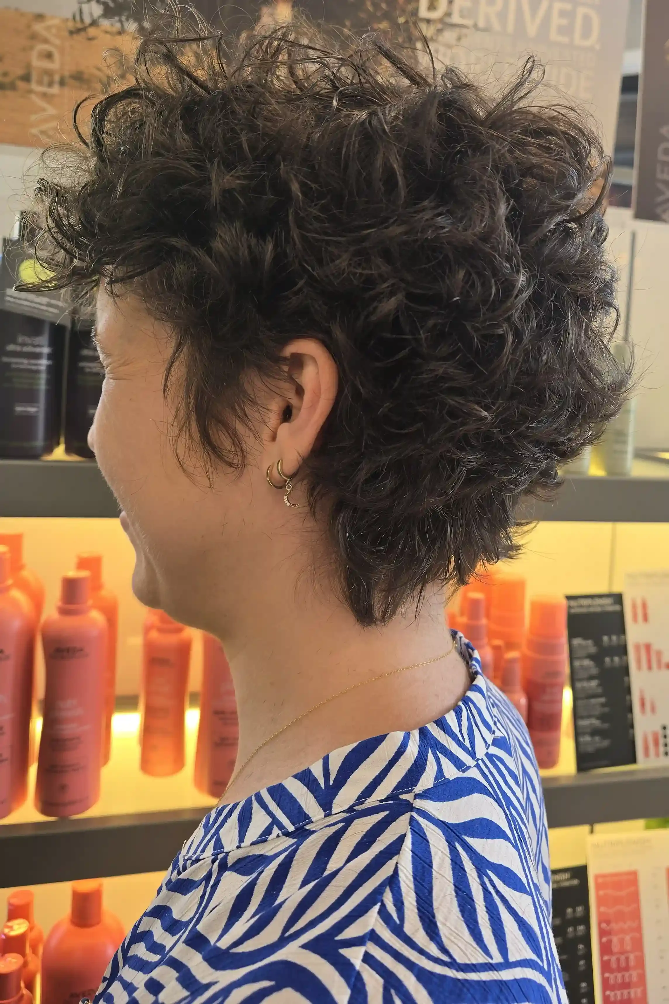 Short curly pixie haircut with soft, natural texture and expertly shaped curls that enhance volume and movement. This modern curly cut is customized to define the hair's natural curl pattern while creating an effortless, low-maintenance style. Haircu