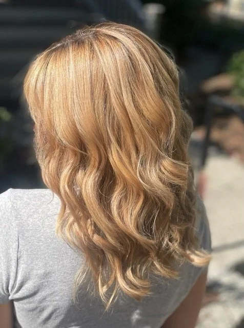 Golden blonde Aveda balayage with soft waves and sunlit dimension, styled at Chroma Salon Seattle for a natural, radiant finish.
