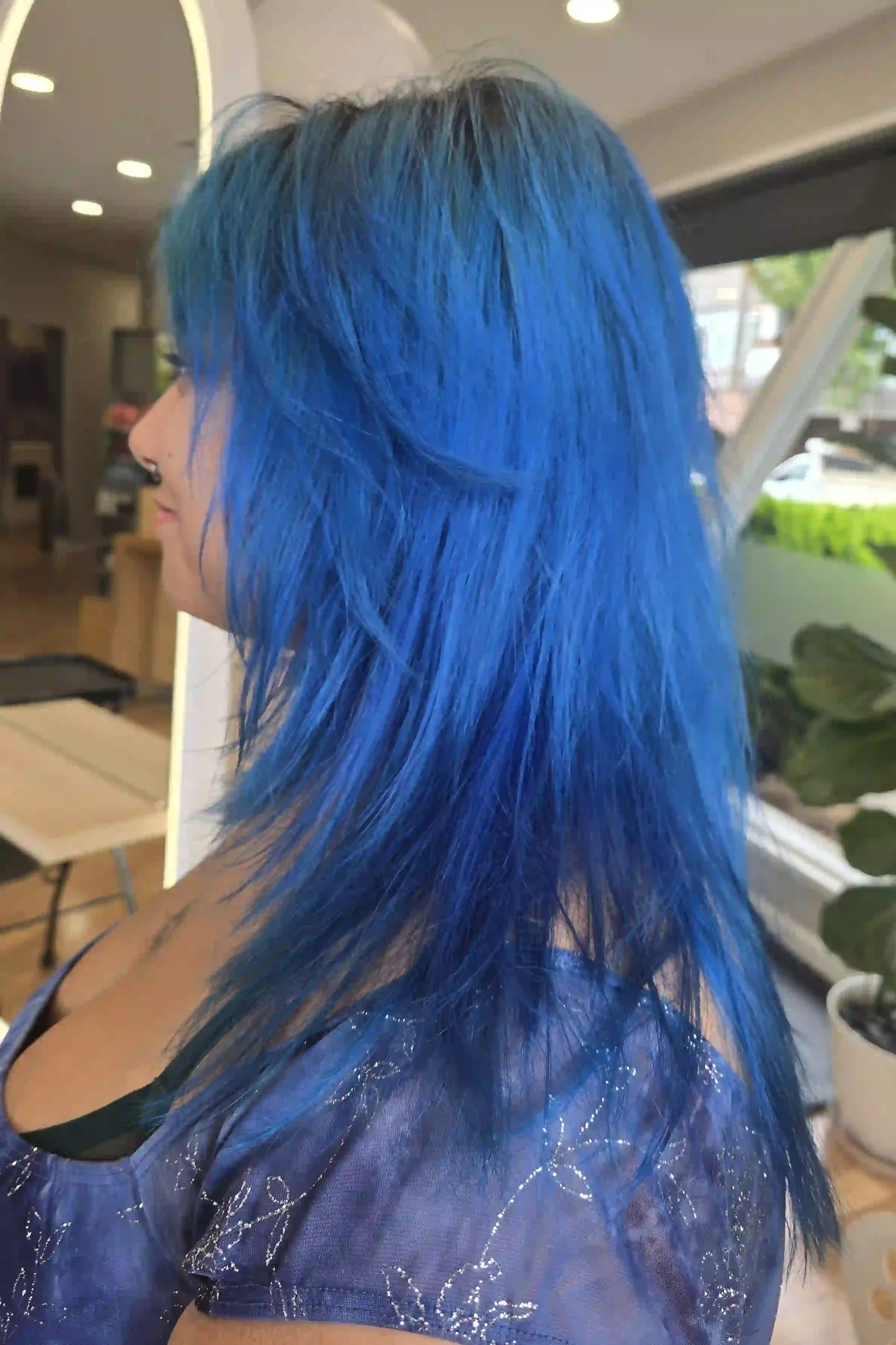 Bold, electric blue hair with vibrant cobalt and deep sapphire tones, creating striking dimension throughout. Long, textured layers and wispy, face-framing pieces give this vivid fashion color an edgy, effortless finish. Hair by Jhana at Chroma Salon