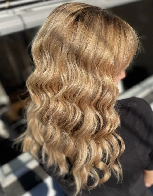 Golden blonde balayage with soft waves and dimensional shine, styled with Aveda products at Chroma Salon Seattle for a natural, sunlit look.