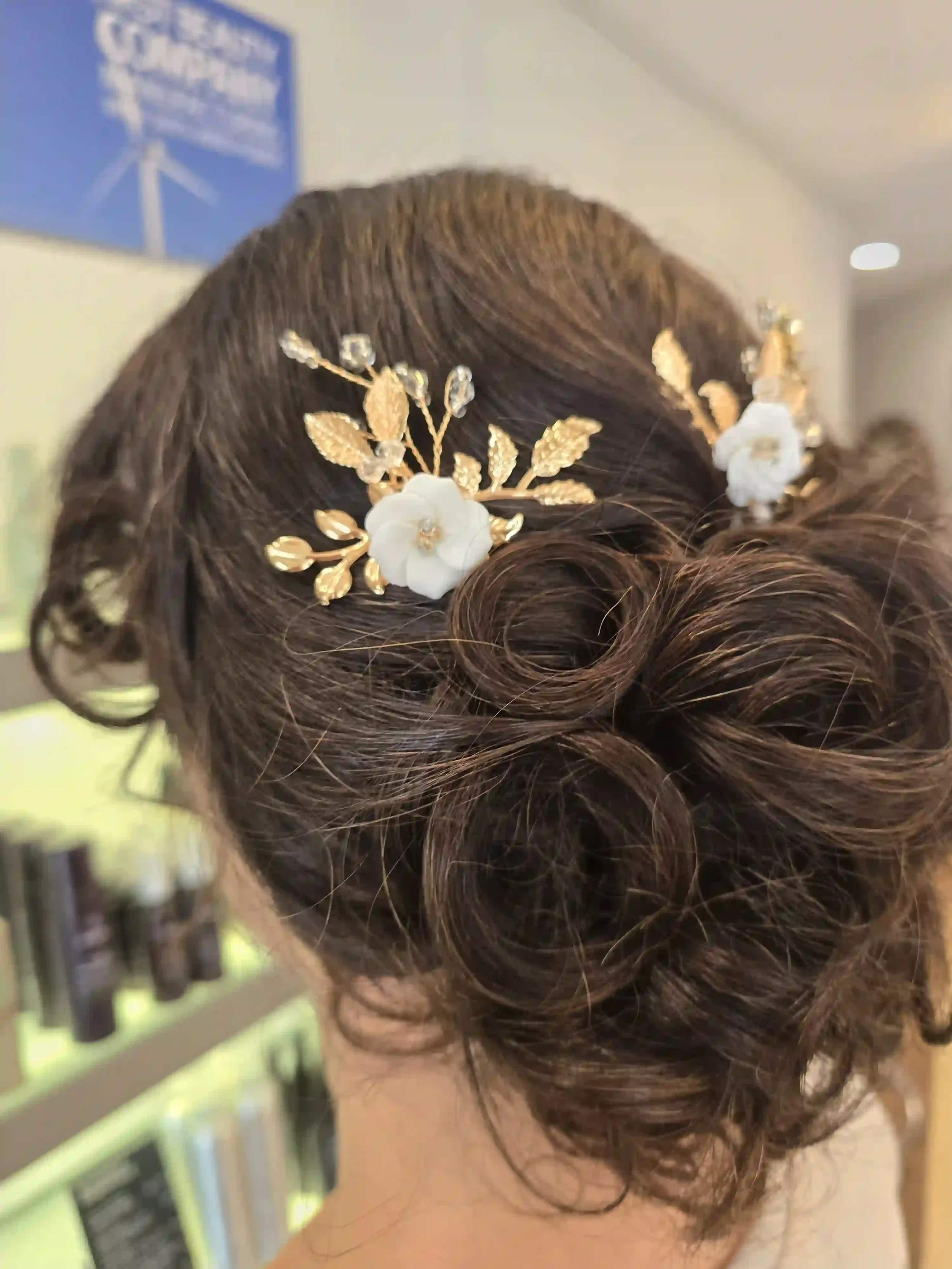 Romantic brunette bridal updo with soft curls and gold floral hair accessories, styled by Jhana at Chroma Salon Edmonds.