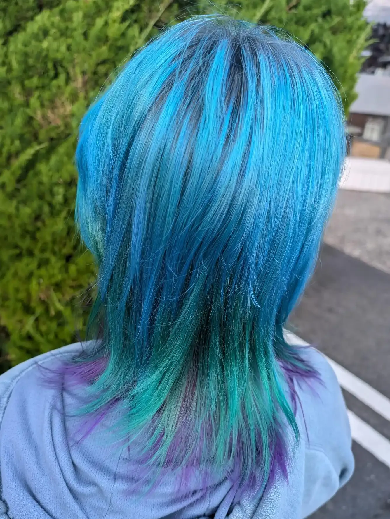 Vivid electric blue fashion color with aqua and violet accents melting through a modern shag mullet haircut. Bold placement and layered texture create movement, dimension, and a vibrant mermaid-inspired finish.