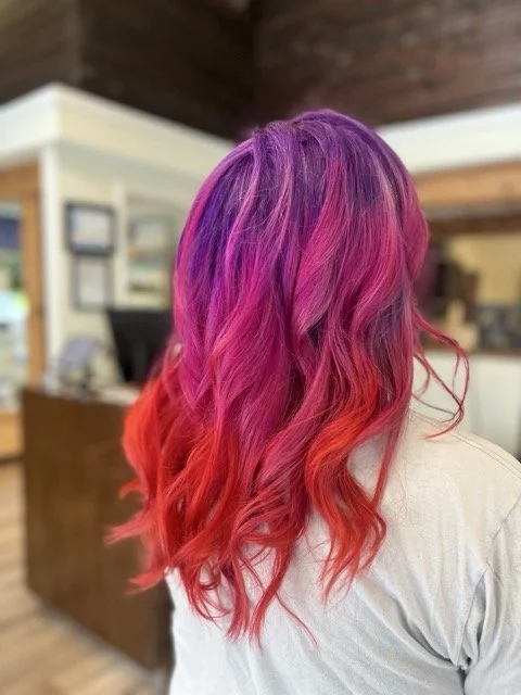 Bold purple, magenta, and red ombré hair color styled at Chroma Salon Seattle. Expert hair color specialists create vibrant, multidimensional looks for standout style.