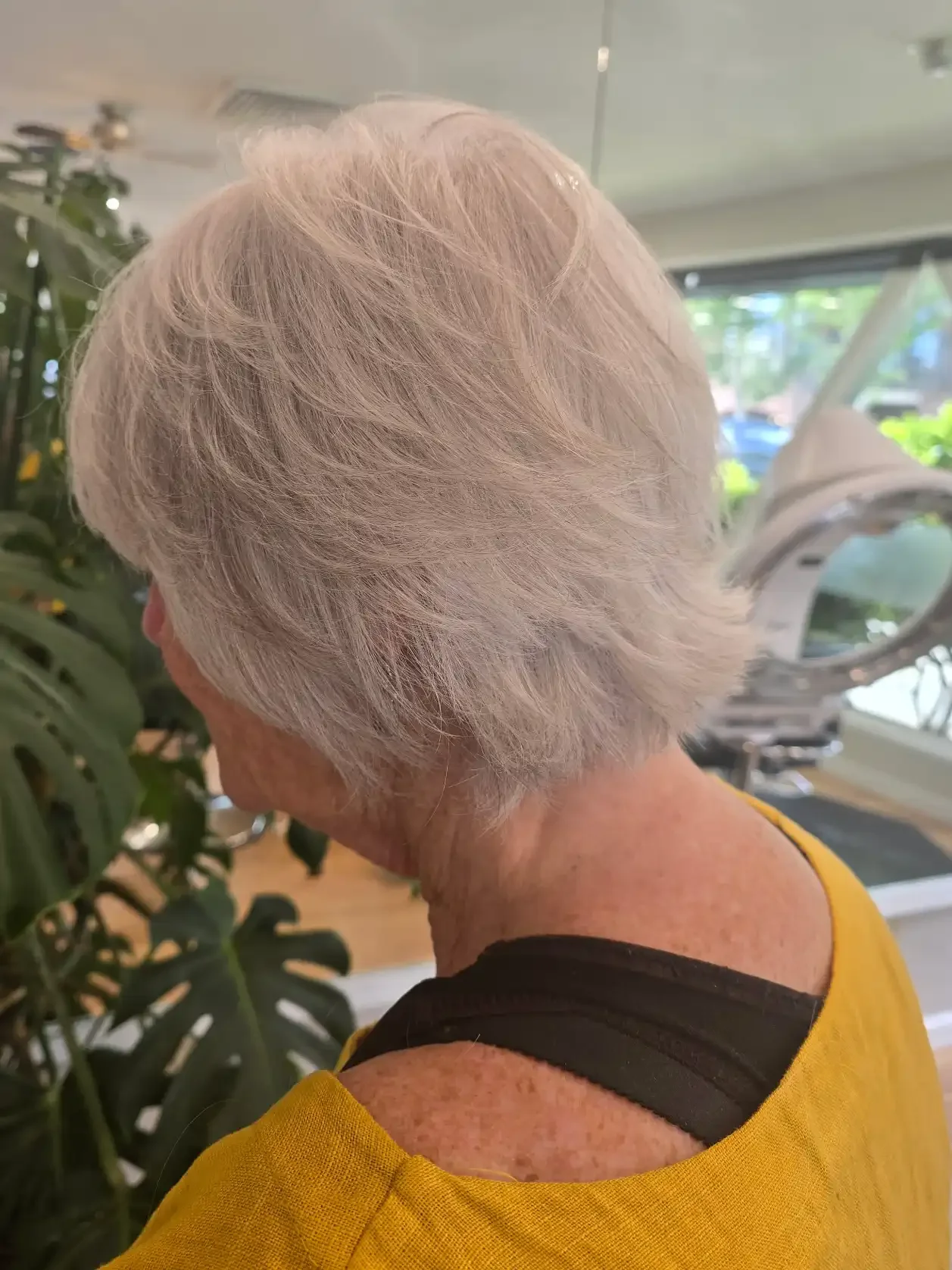 Soft silver pixie bob featuring expertly blended gray coverage and feathered layers that create movement, volume, and a lightweight finish. The shape softly hugs the neckline while maintaining fullness through the crown, offering an elegant, low-main