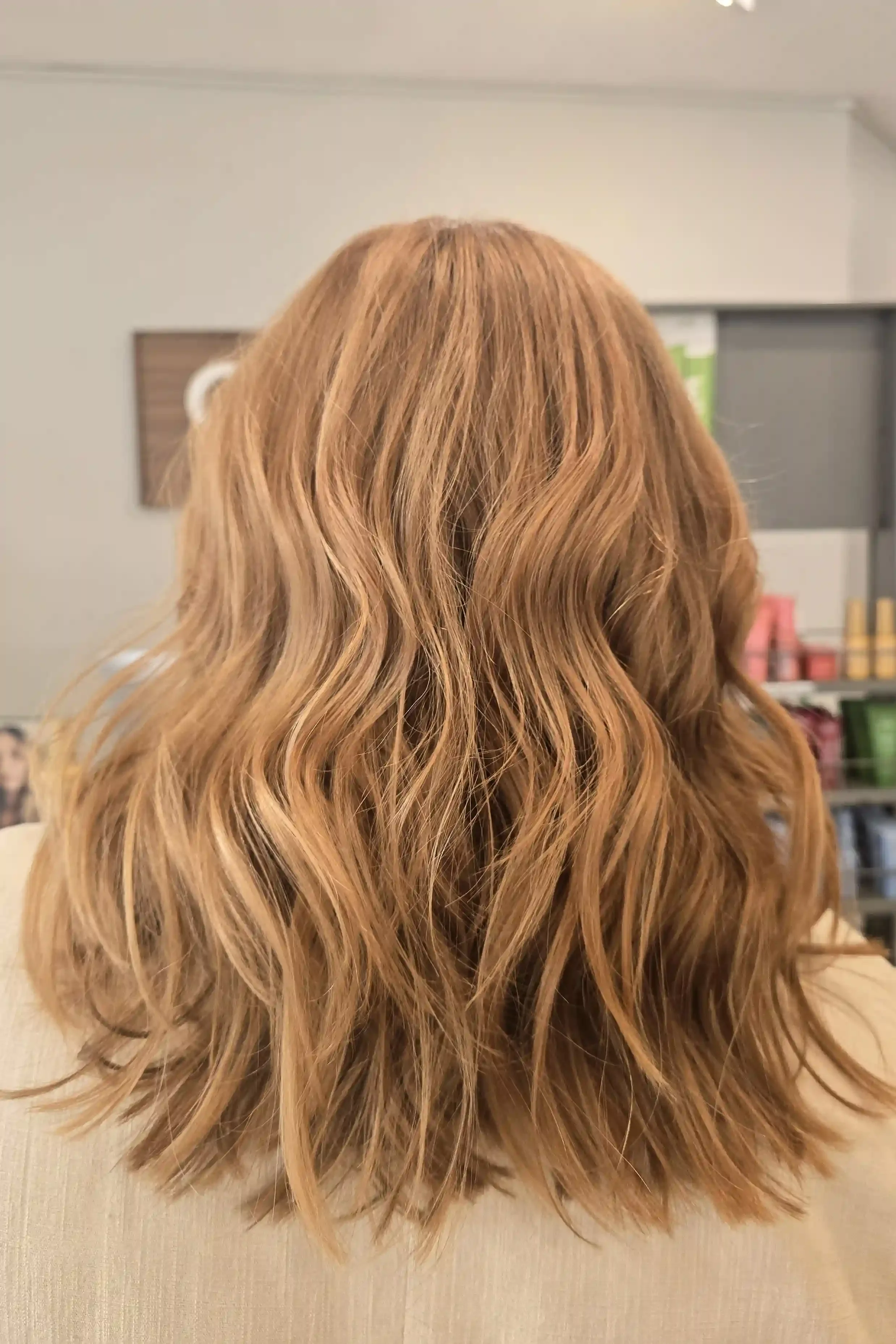 Strawberry blonde balayage with warm copper and golden blonde dimension on a textured long bob, styled with soft, effortless waves. The natural blend creates a luminous, lived-in finish with rich warmth, shine, and movement. Hair color and styling by