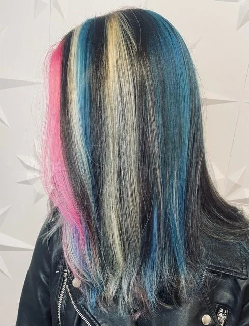 Bold fashion hair color with pink, platinum, and teal panel highlights on dark hair, created at Chroma Salon Seattle by expert vivid hair color specialists.