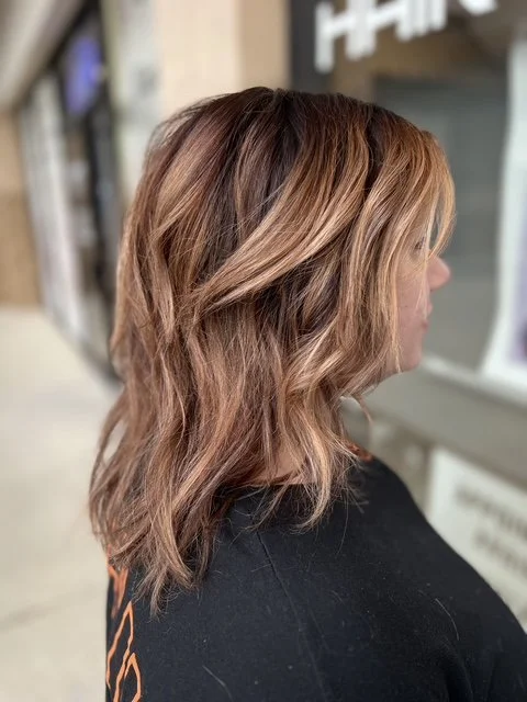 Layered brunette balayage with soft blonde highlights and textured waves, styled at Chroma Salon Seattle for a natural, lived-in finish.