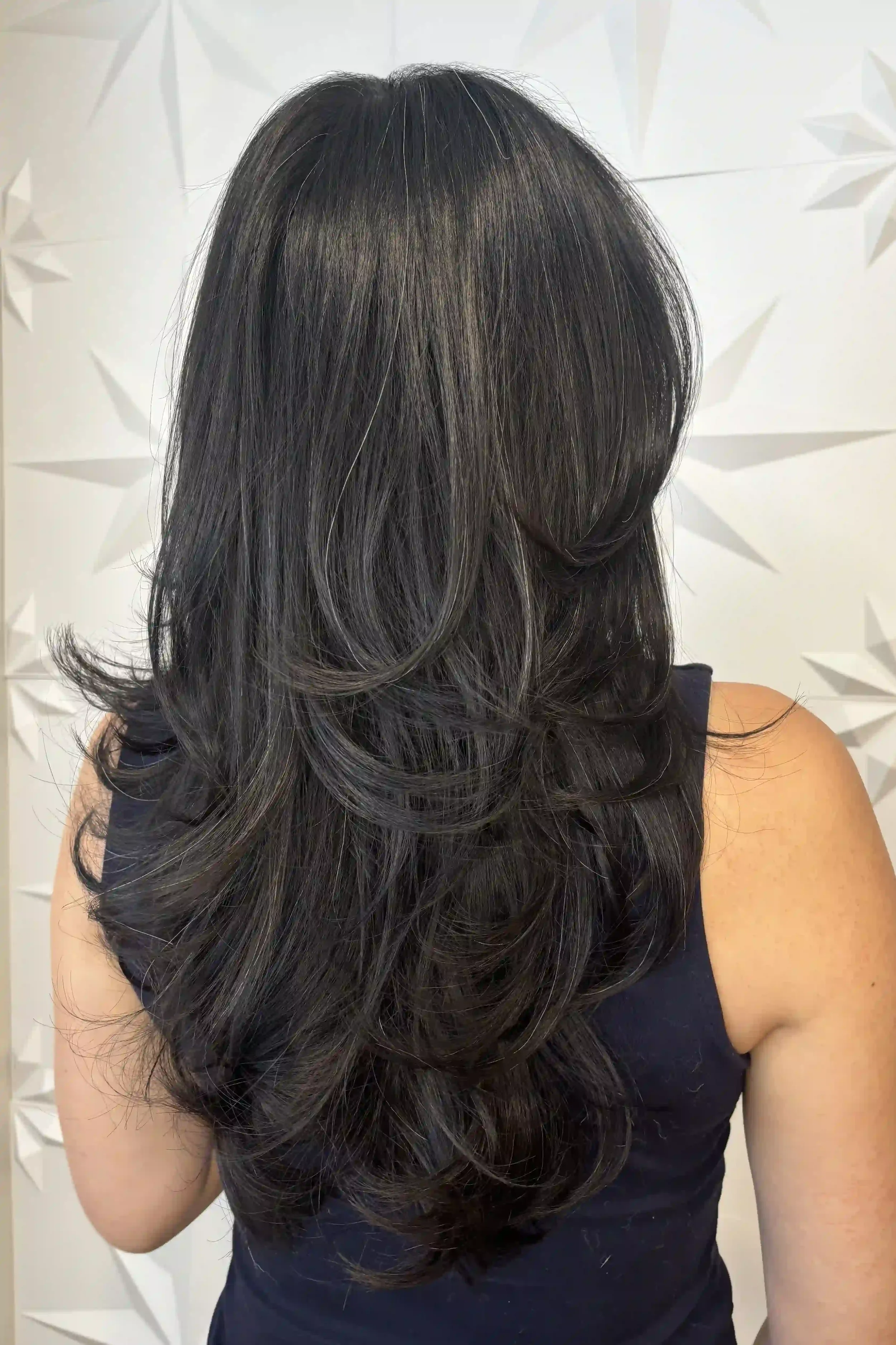 Rich, dark brunette hair with long, cascading layers and soft, feathered ends. A voluminous blowout creates beautiful movement, a smooth, glossy finish, and flowing layers that frame the face. Hair by Alpin at Chroma Salon Queen Anne.