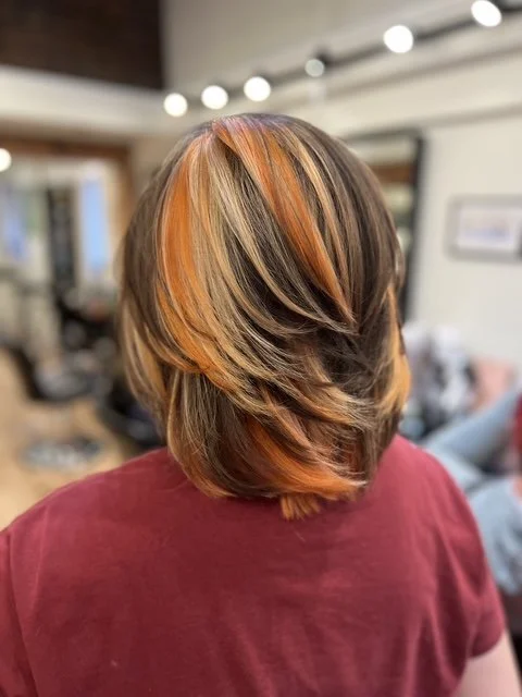Layered brunette bob with bold copper and blonde highlights, styled at Chroma Salon Seattle for dimensional color and movement.