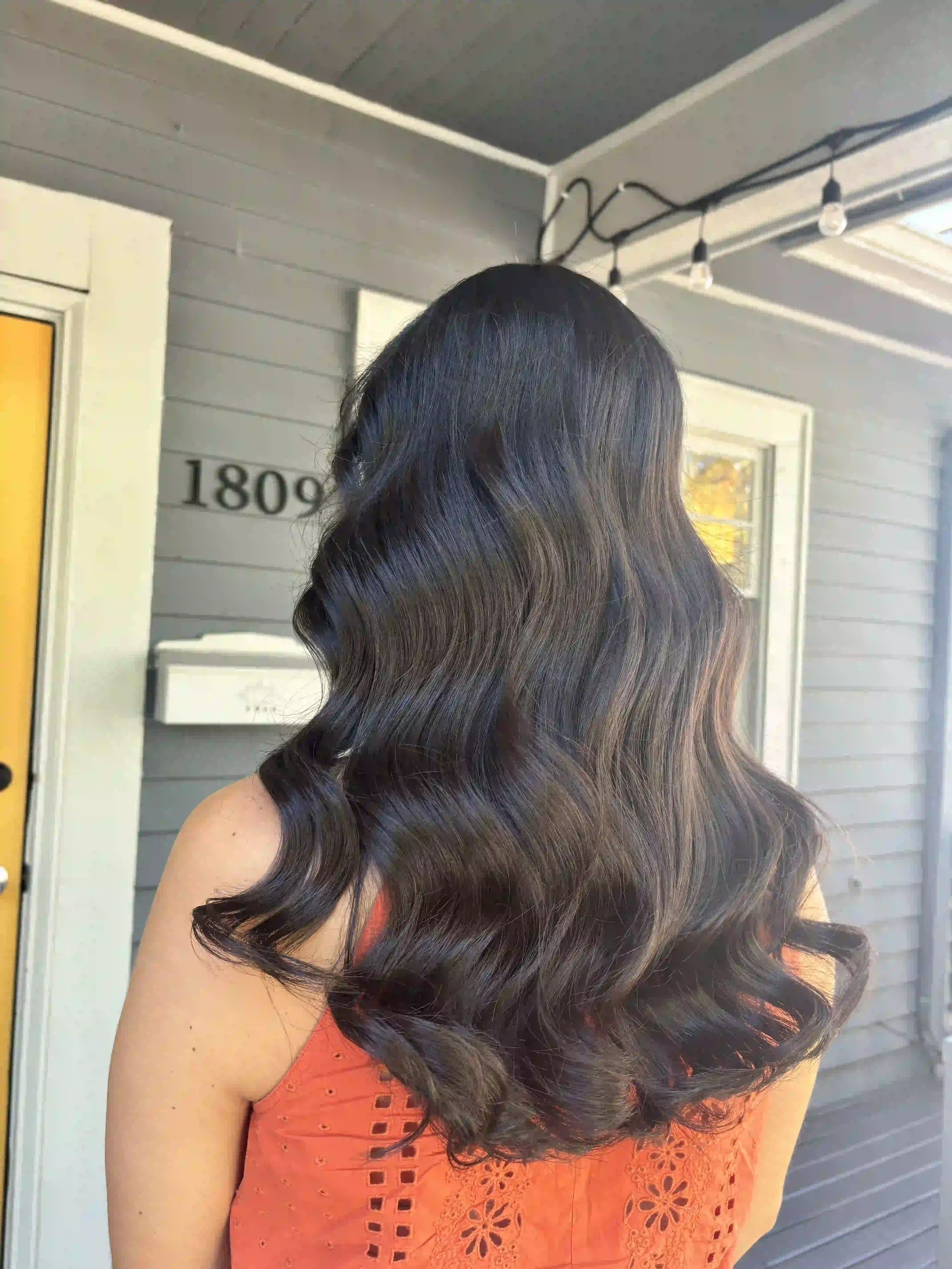 Long dark brunette hair styled in soft glossy waves with a smooth blowout finish, created by Alpin at Chroma Salon Queen Anne Seattle.