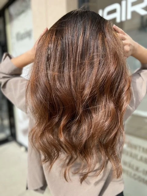 Warm brunette balayage with copper tones and soft, beachy waves, styled at Chroma Salon Seattle for natural dimension and shine.