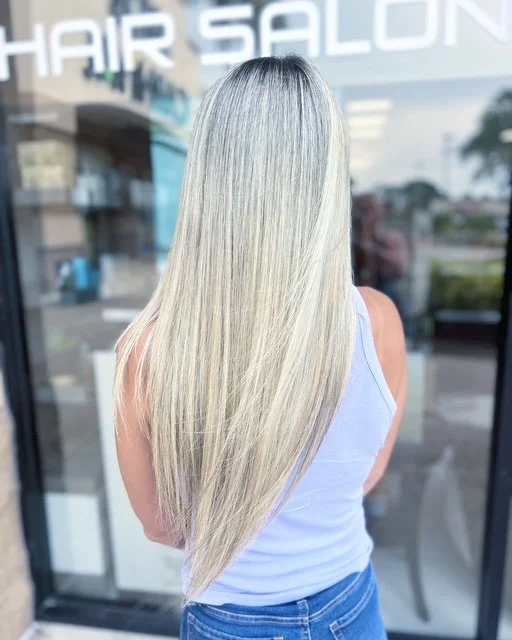 Long platinum blonde hair with dark shadow root and sleek, straight finish, created at Chroma Salon Seattle using professional Aveda blonding techniques.