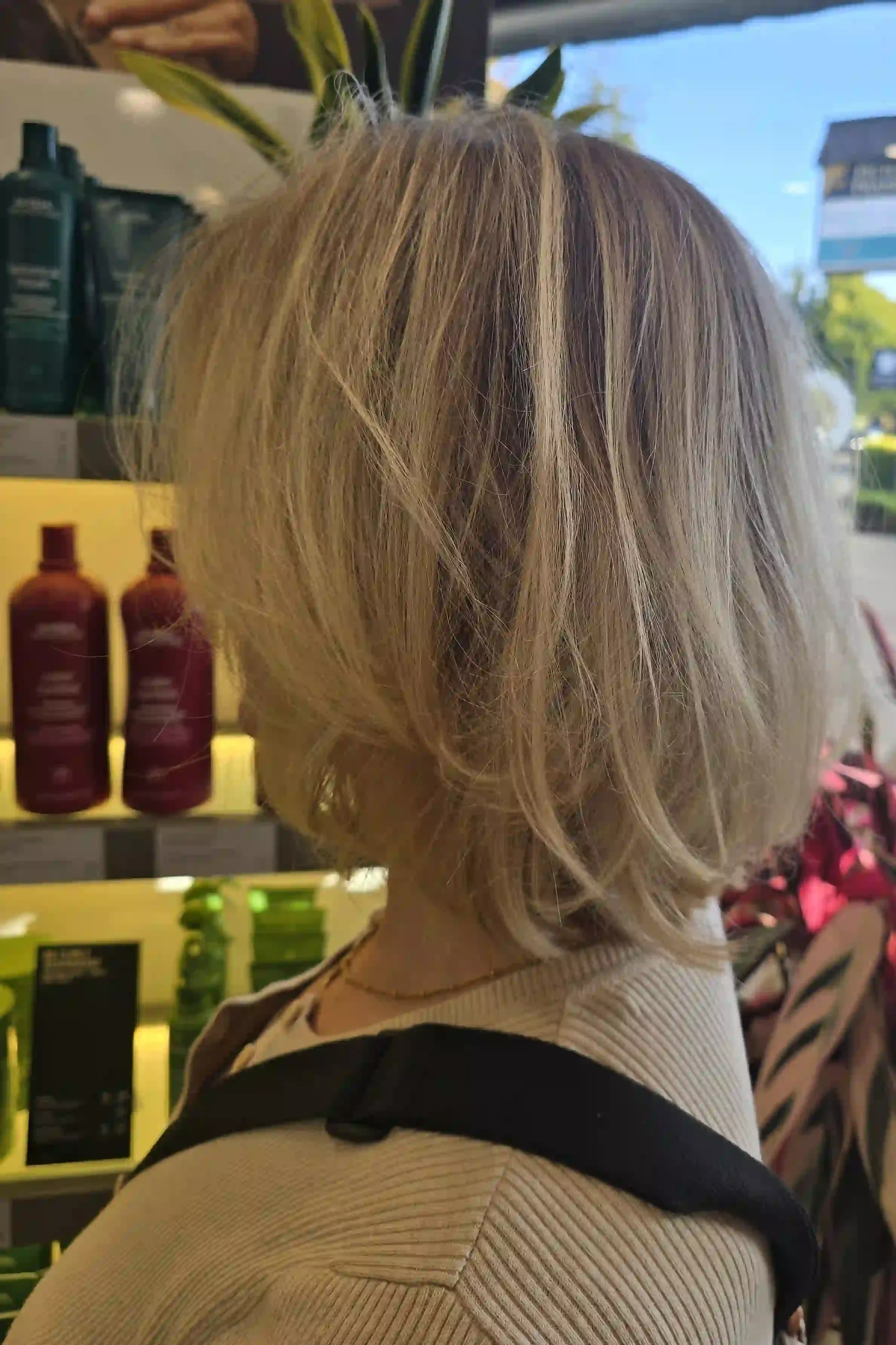 Soft beige blonde hair with a blend of champagne and sandy blonde tones, creating subtle dimension and a natural-looking finish. This voluminous, chin-length layered bob features airy texture, feathered ends, and gentle movement for a soft, effortles