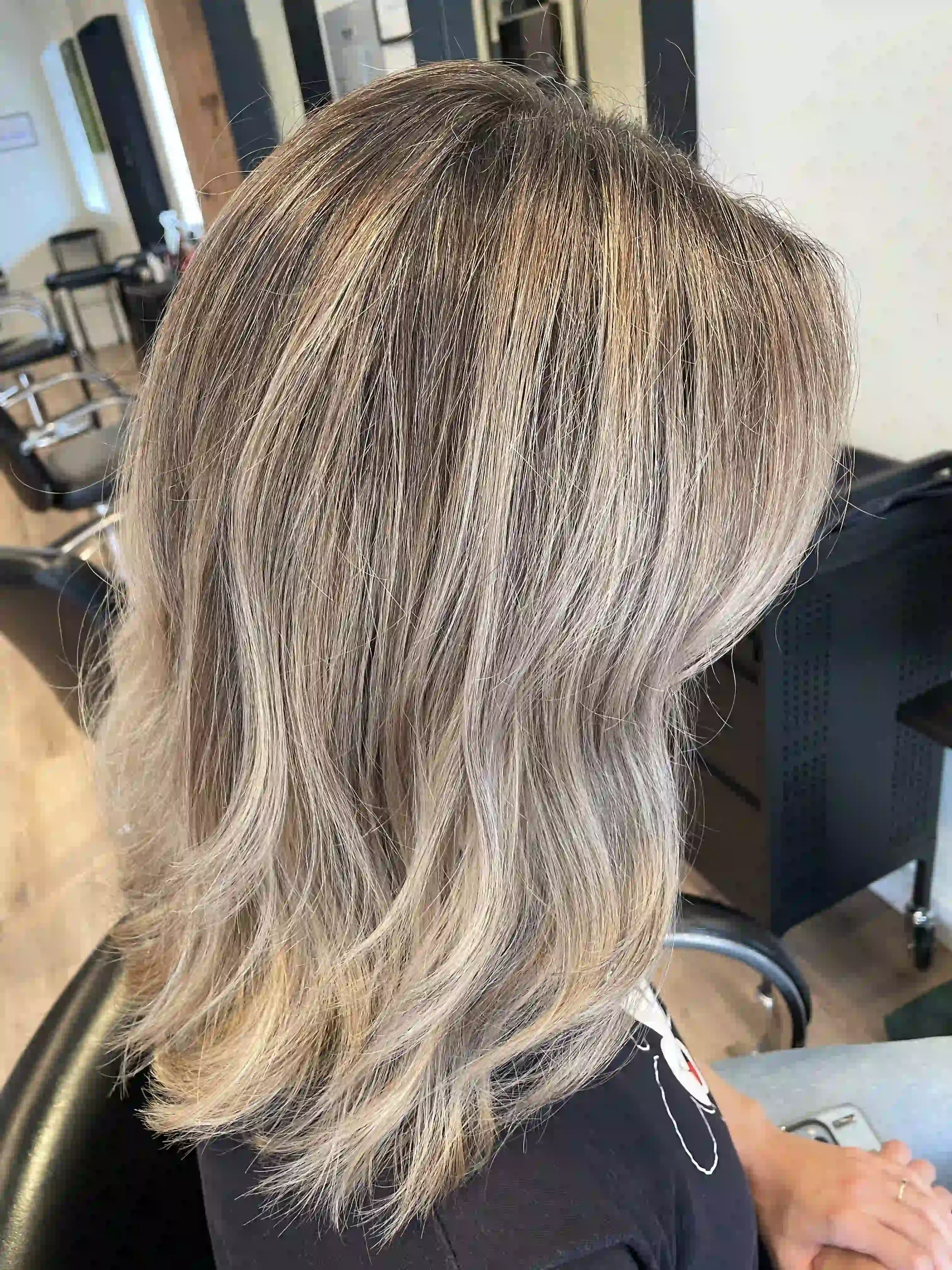 Icy beige blonde layered lob with a soft shadow root, dimensional highlights, and textured movement, styled by Anna at Chroma Salon Wallingford Seattle.