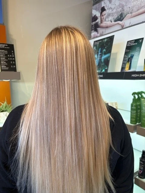 Long, straight blonde hair with seamless highlights and glossy finish, created at Chroma Salon Seattle using professional Aveda blonding services.