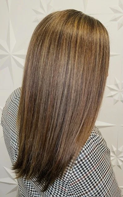 Warm brunette with subtle caramel highlights and a smooth, layered finish, created at Chroma Salon Seattle using professional Aveda hair color.