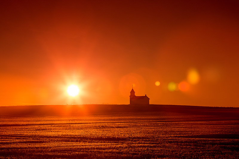 The former Bethany Lutheran Church, now abandoned, sits high atop the Montana plains north of Dunkirk as the rising sun back lights it and creates a wonderful silhouette and adds some lens flare at the same time.&nbsp;→ Buy This Print