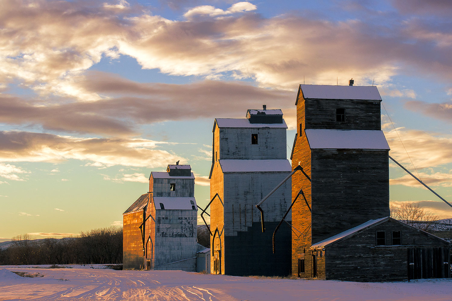 A row of grain elevators illuminated by the last light of the day in what is downtown Loma, Montana...population 92. Photograph was taken with the Samsung NX300 mirrorless camera.&nbsp; &nbsp;→ Buy This Print