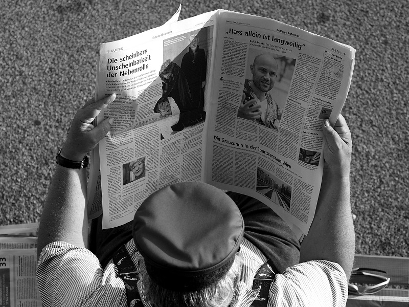 A man reads a newspaper on the streets of Salzburg, Germany. Photo by Thomas Geiregger.