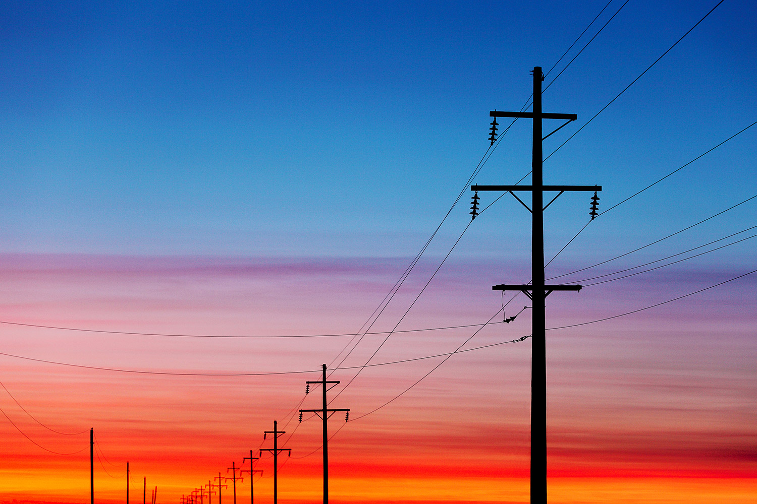 The sunrise to the ease silhouettes this row of electrical poles and power lines near Fairfield, Montana.&nbsp;→ Buy a Print