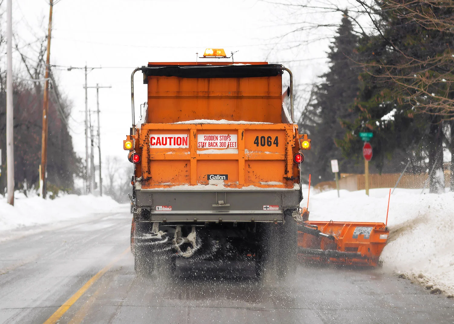 A snow plow removing snow and spreading some salt. → License Photo