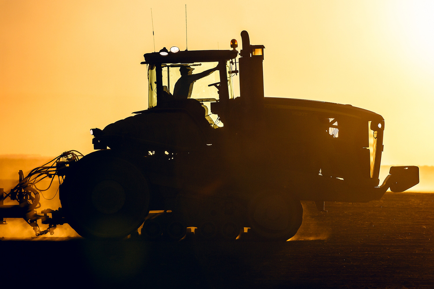 A silhouette of a John Deere tractor seeding wheat on a farm near Chinook, Montana.&nbsp;→ License Photo