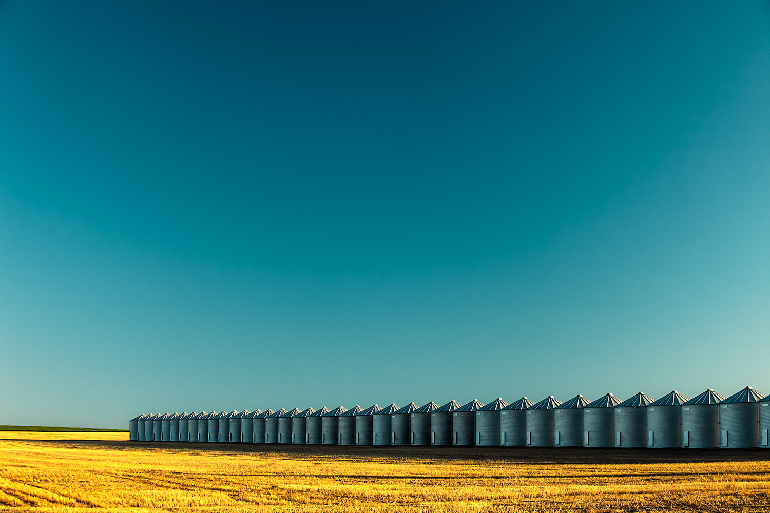 A long line of grain bins on a wheat farm near Kremlin, Montana.&nbsp;→ Buy a Print