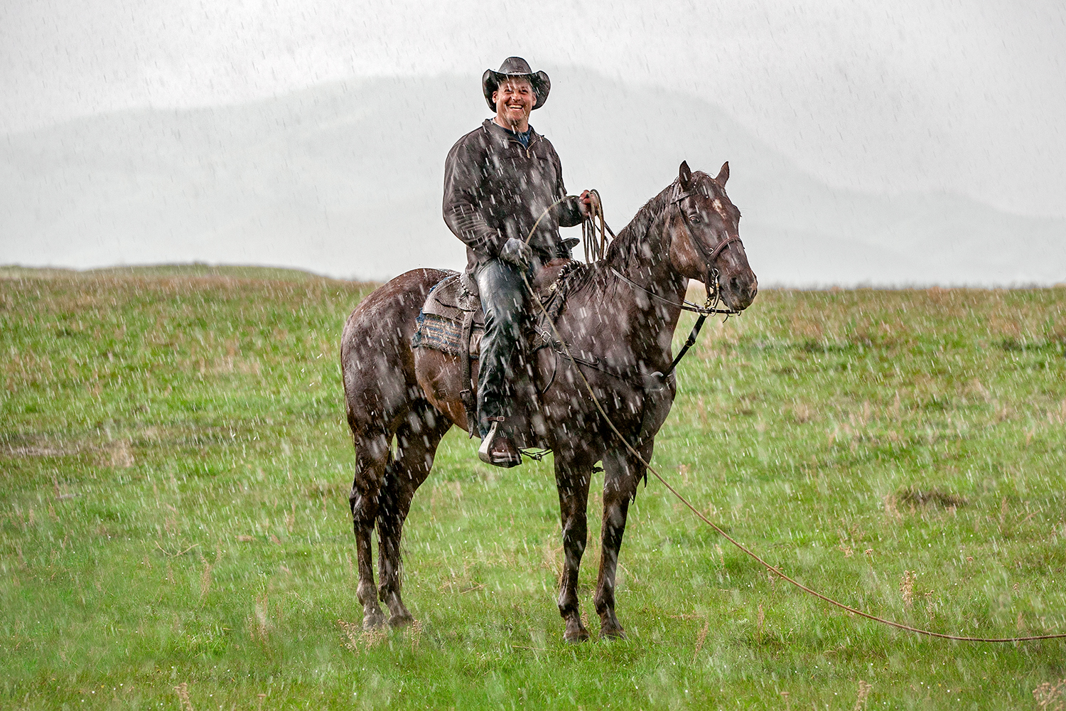 Cowboy Riding Horse in the Rain Smiling