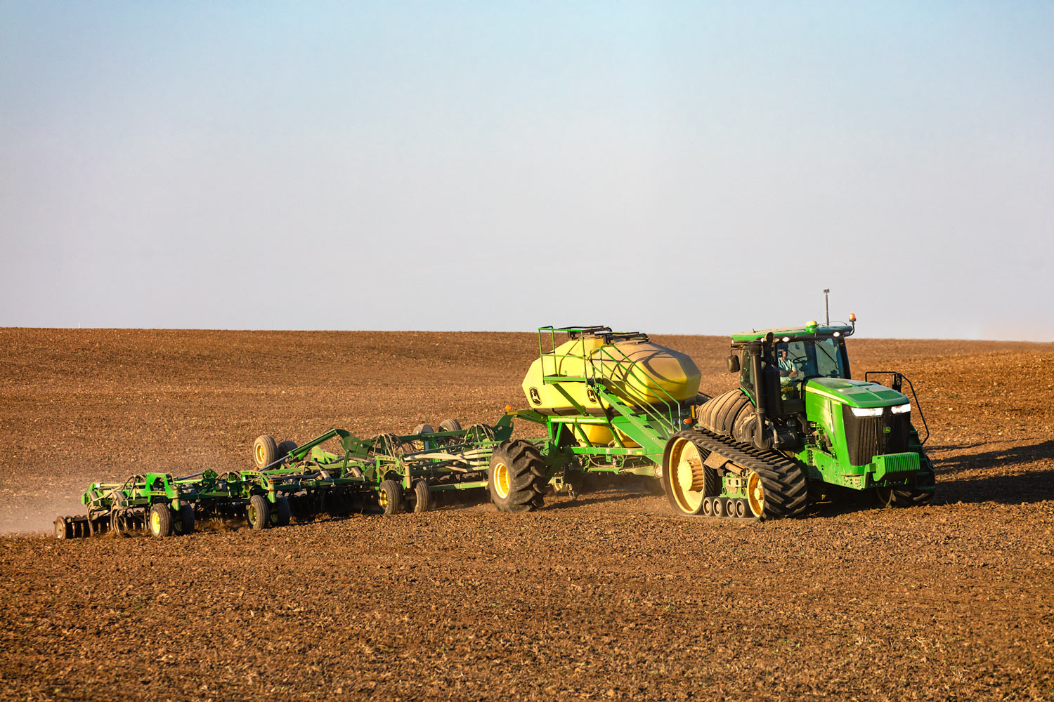 A farmer seeds wheat on an organic farm with a John Deere tractor and air drill south of Chinook, Montana.