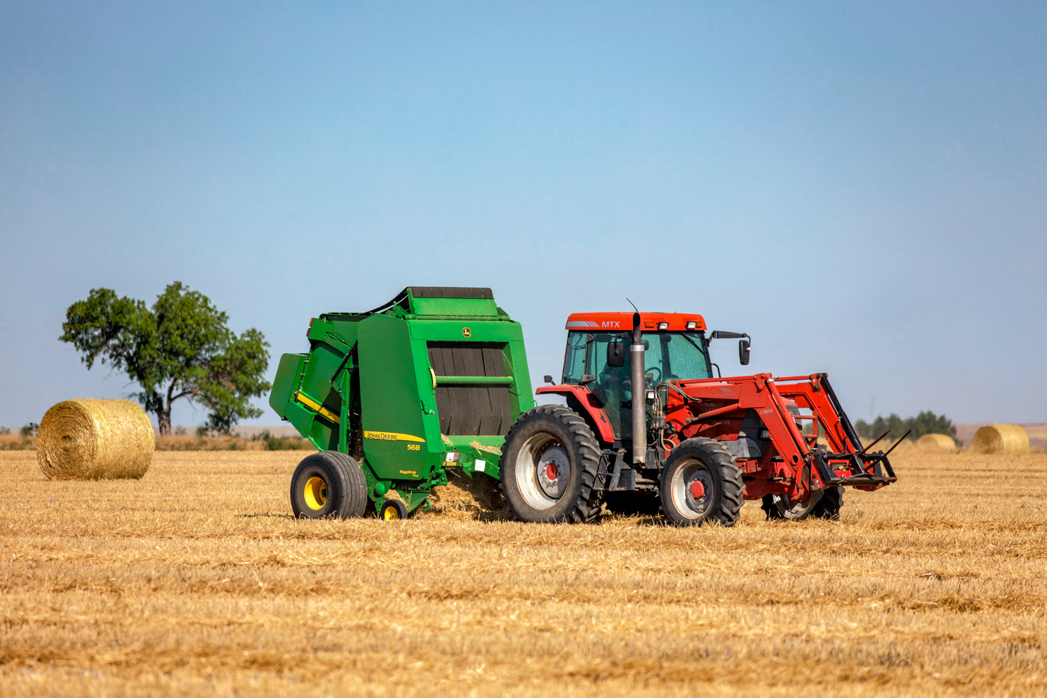 A McCormick tractor and a John Deere baler baling wheat straw near Brady, Montana.