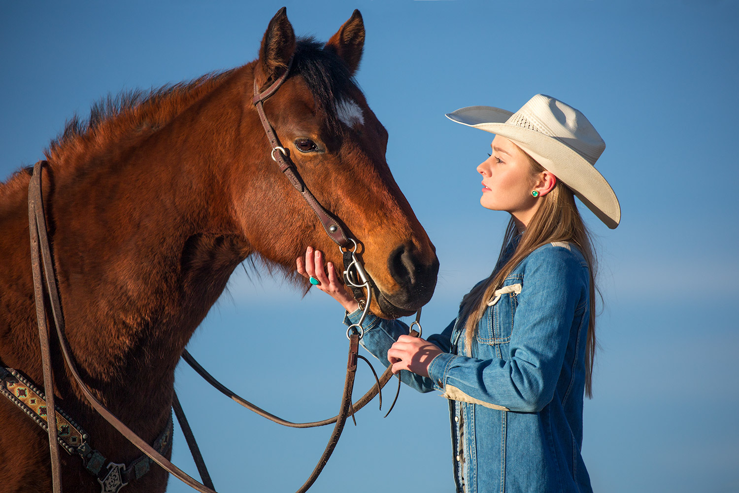 Another cowgirl photo of a young woman petting her horse on a ranch near Bozeman, Montana.