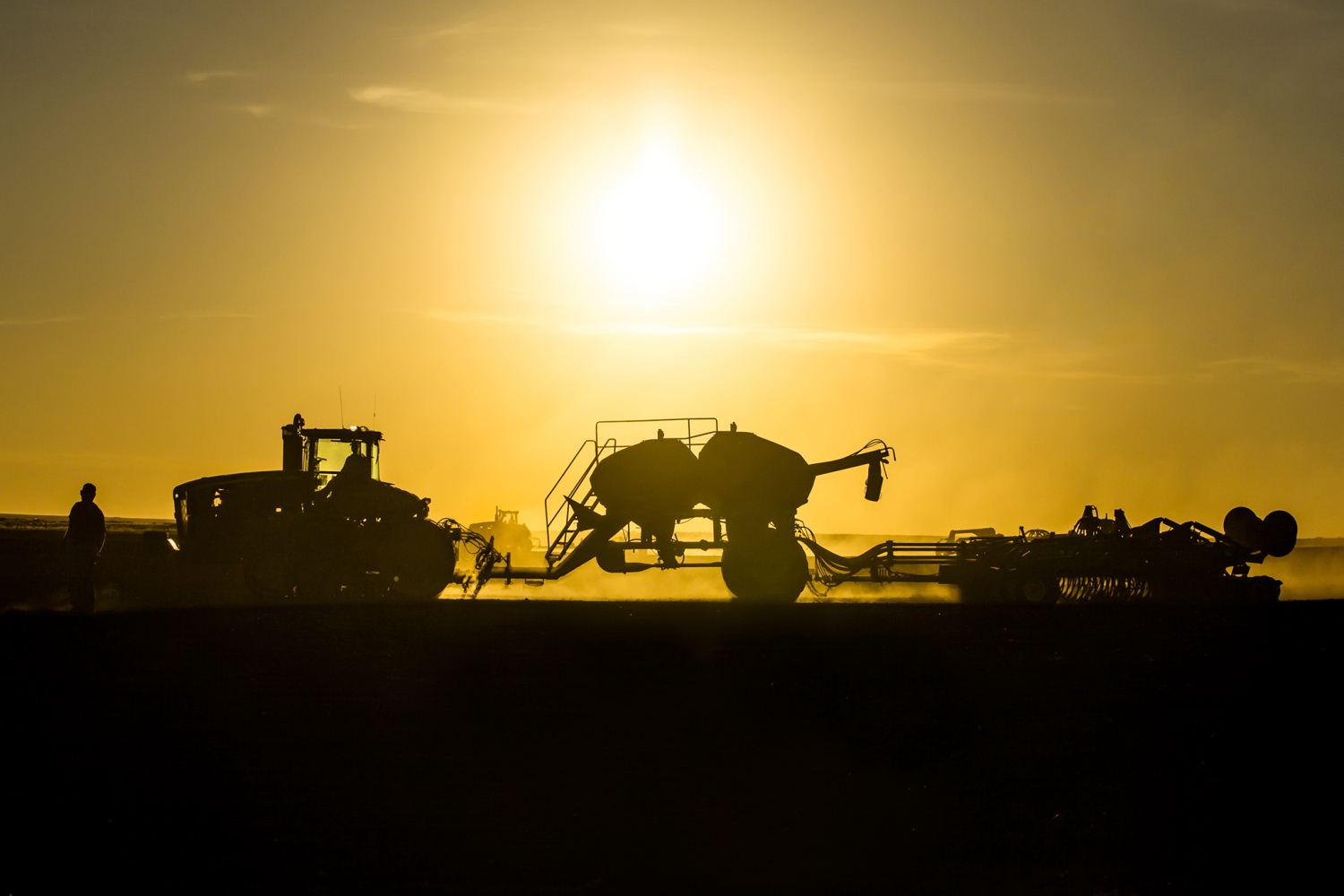 A silhouette of farm equipment seeding wheat on a farm north of Chinook, Montana.&nbsp;→ License Photo