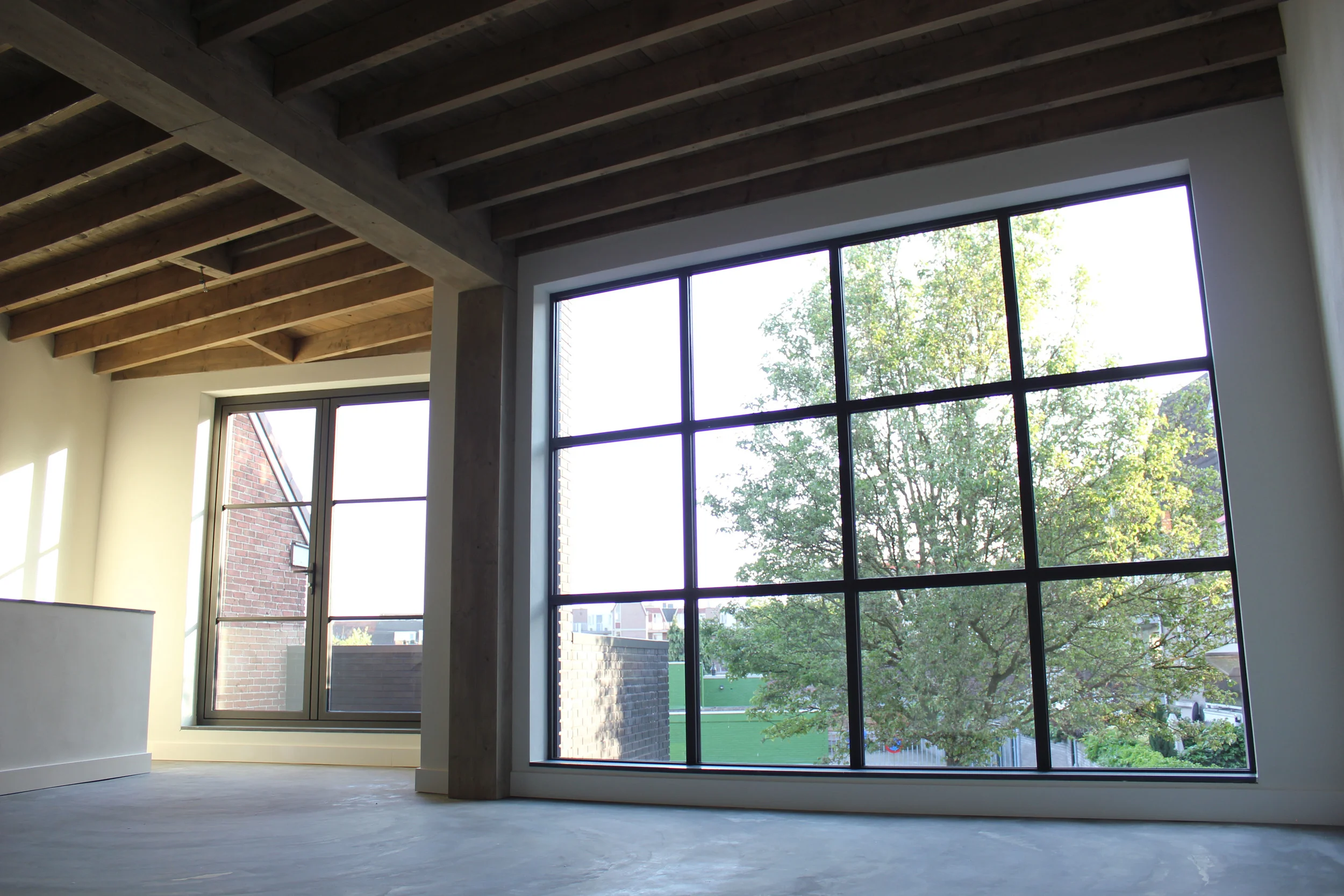  De betonnen vloer, de grote raampartijen en de houten plafonds zijn bepalend voor de industriële maar warme sfeer 