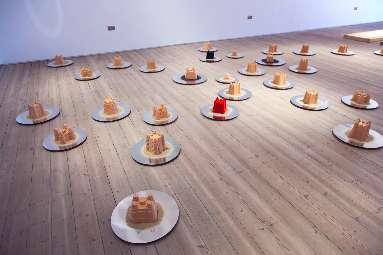  The project  In Limbo  explores the idea of childhood memories and how we construct ourselves as individuals. This installation is made of silicone casts mounted on sand on mirrored discs dispersed on the floor. At once the sand castles are familiar