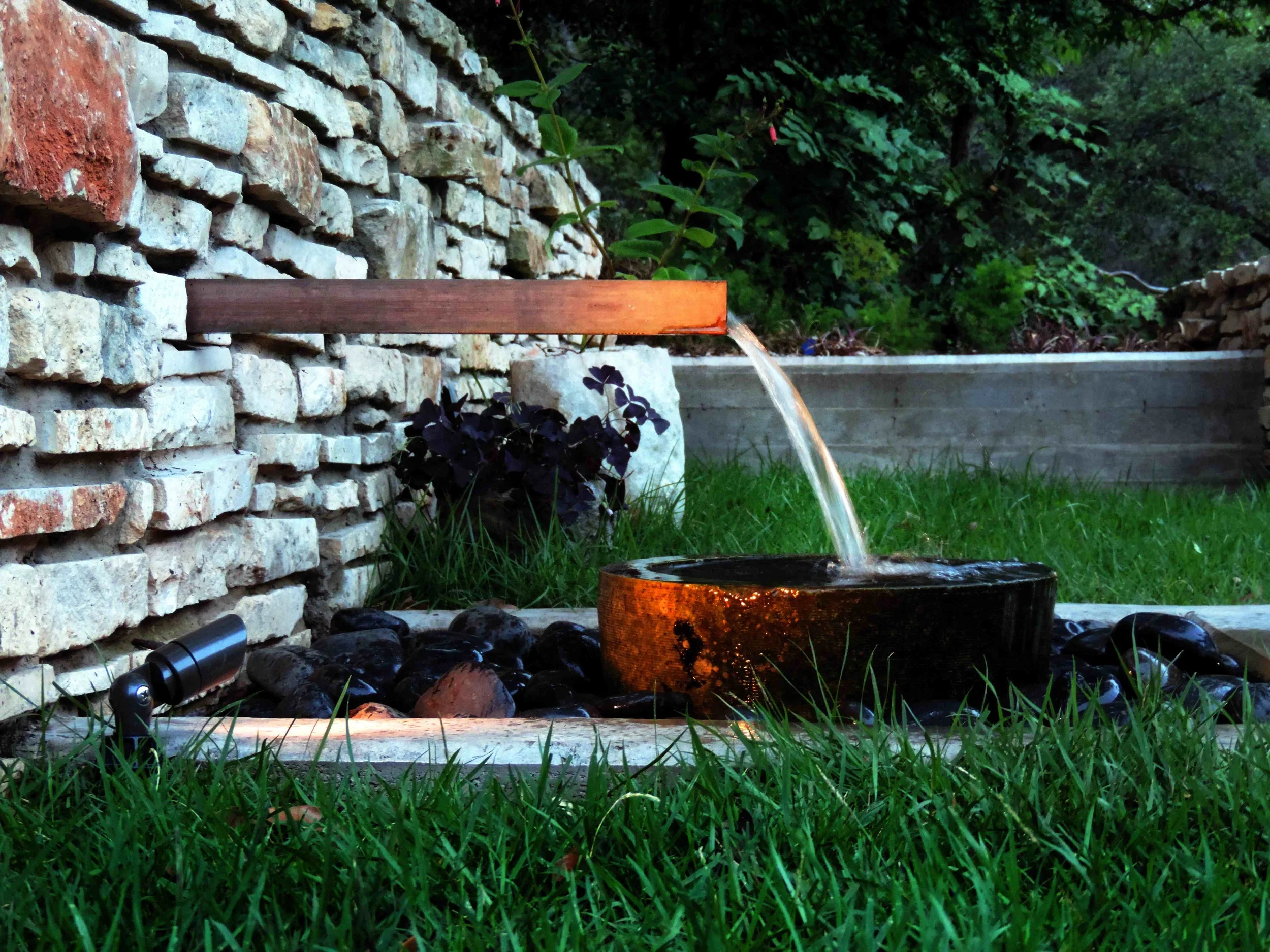 outdoor lighting can highlight a feature, like the flow of water from a fountain