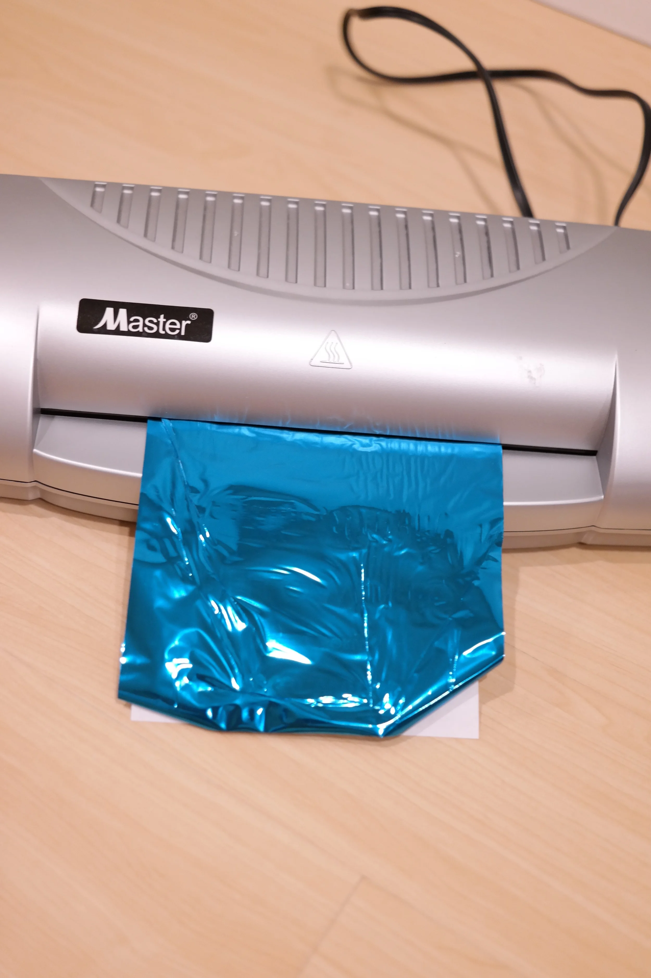 Align the foil on top of the print and run trough laminating machine at least 3-4 times before you peel off the foil