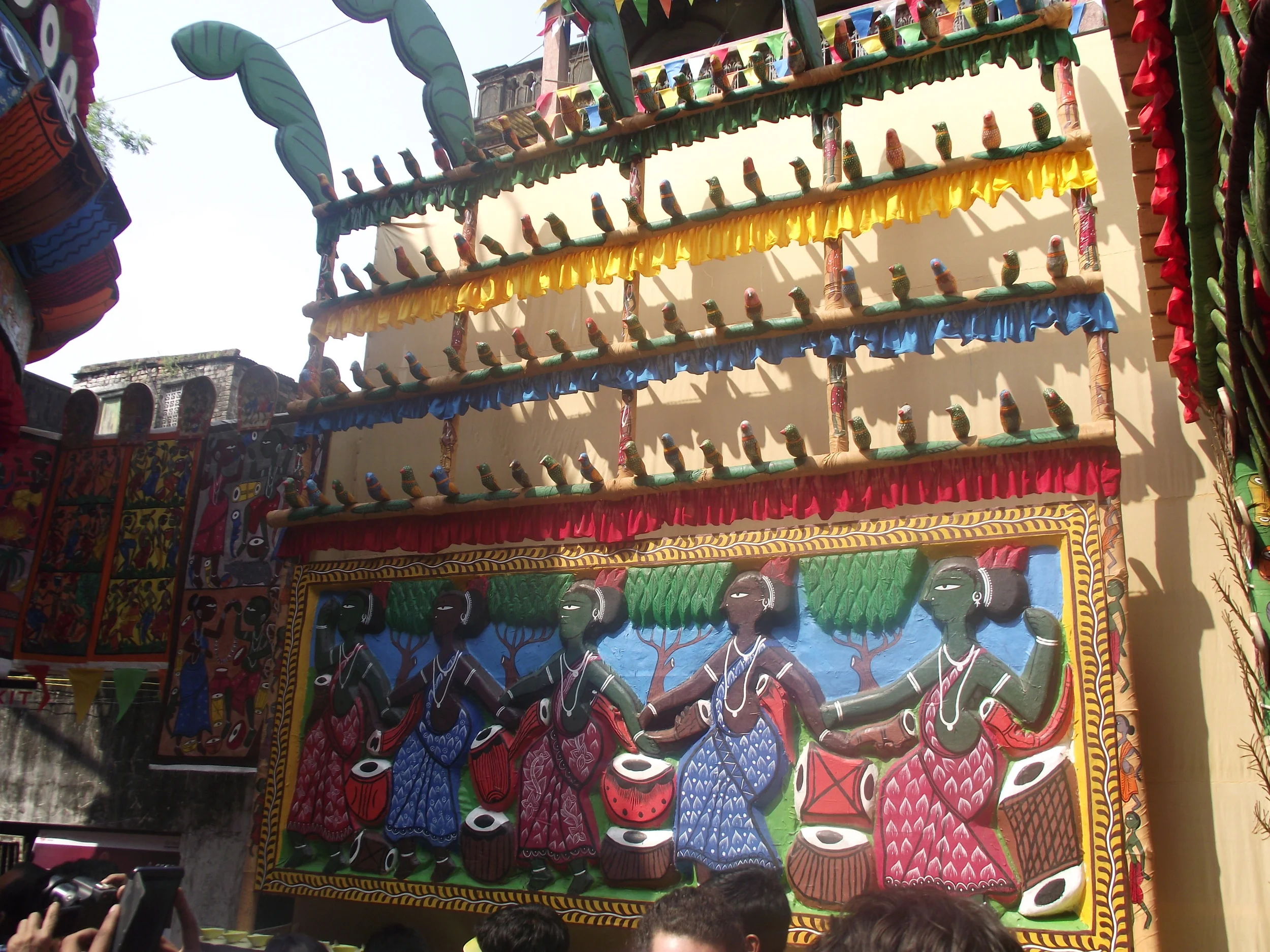  The walls of the pandal had imaginative canvases of the village. The unmarried tribal ladies of the village are performing a dance and in the distance one can see a series of   Karam   trees. 