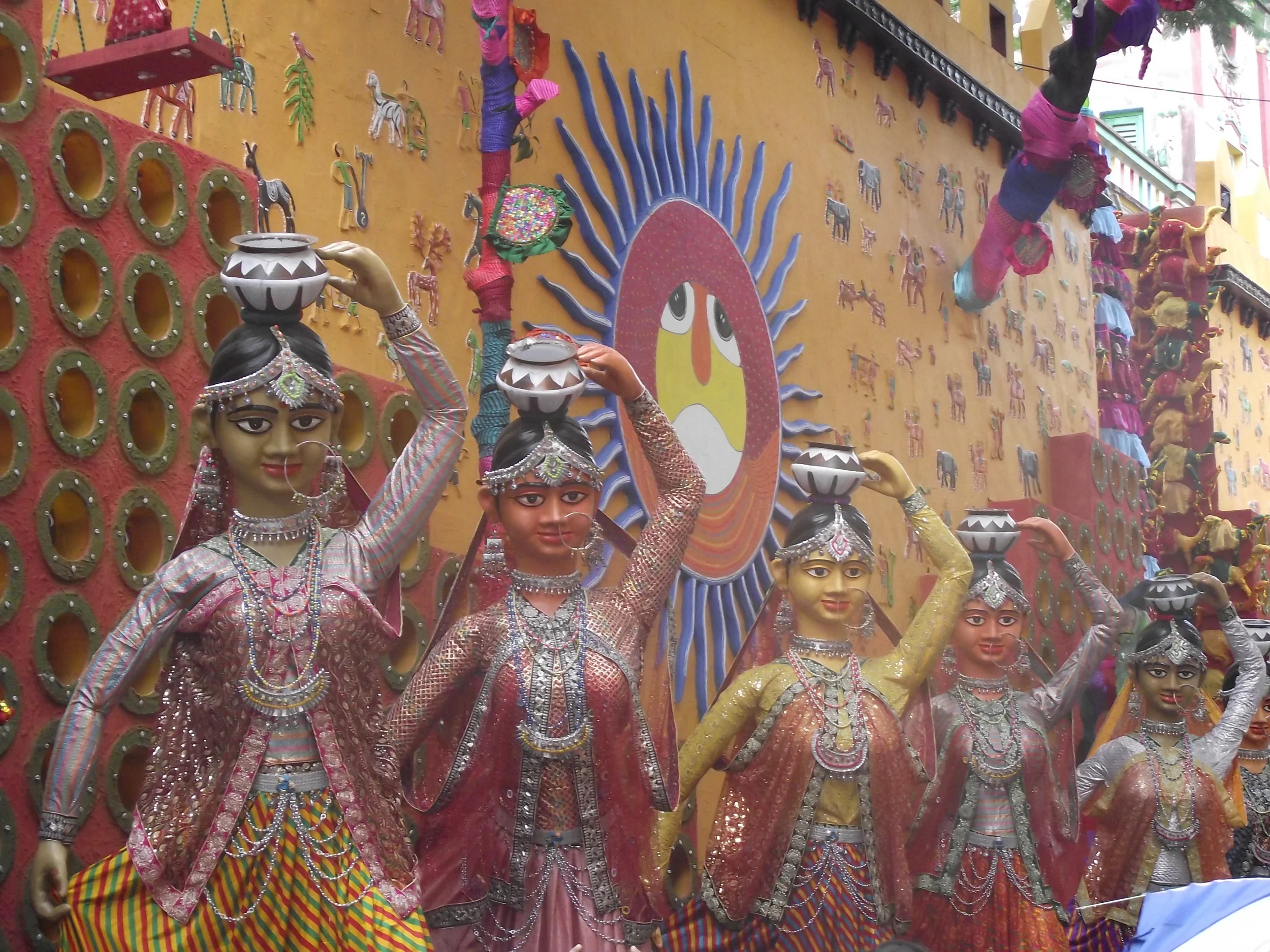  Extravagant stuff. Look at the detailing of custom and attire in each figure! The sungod (crucial belief in Rajasthan)&nbsp;painted in the backdrop wall. Small observation: The pots on the heads should have been proportionately bigger :) 