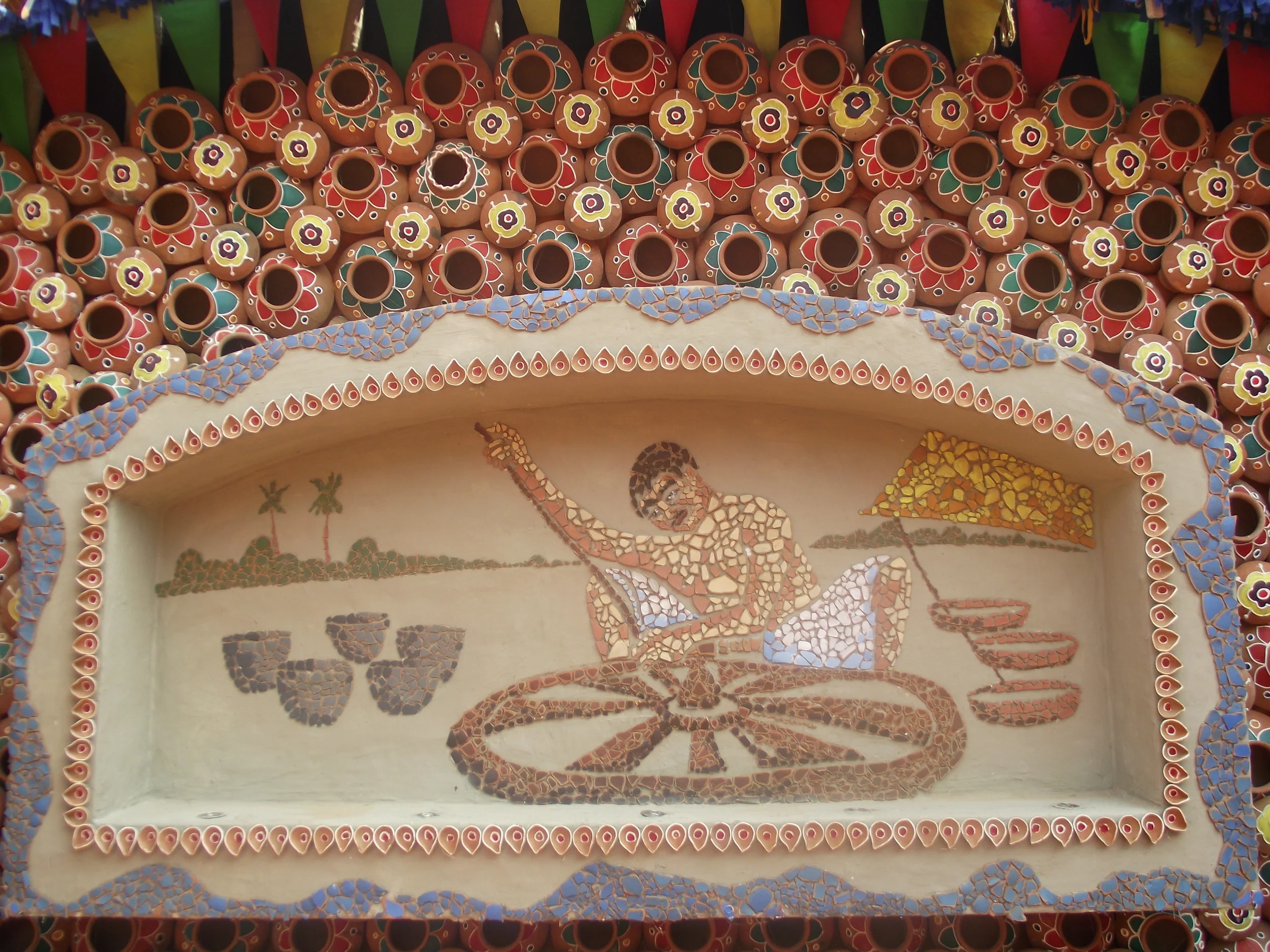  This frame focuses on a terracotta artist making clay pottery. (Notice the way clay pots are arranged in the top of the canvas they way they are decorated with multi colours) 
