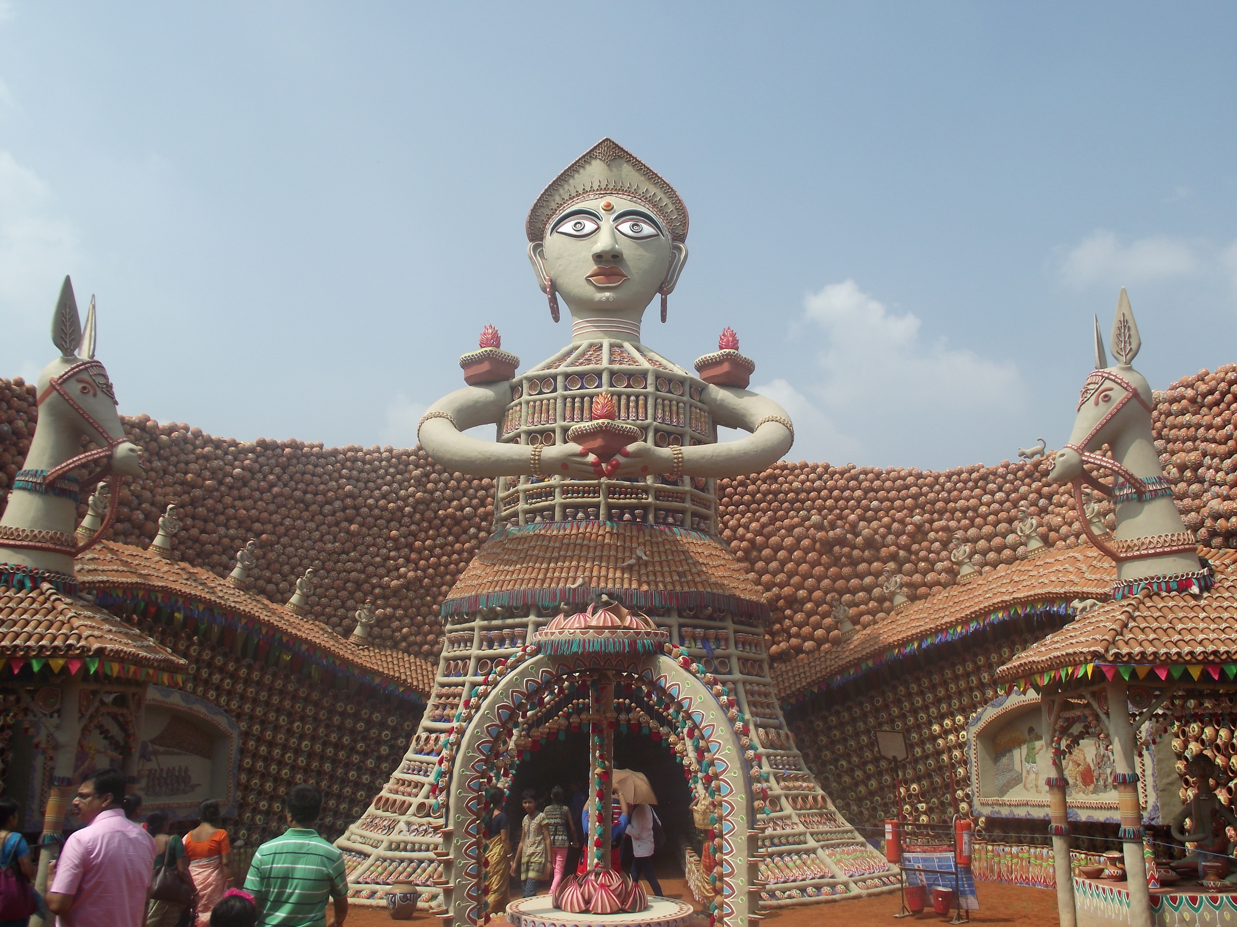  Long shot with the entire front view of the pandal premises. You can see the huge spread over which Shakti Sharma created pandal. The centre of the premise had the large symbolic figure of a lady through which the artist wanted to talk about Bishwa 