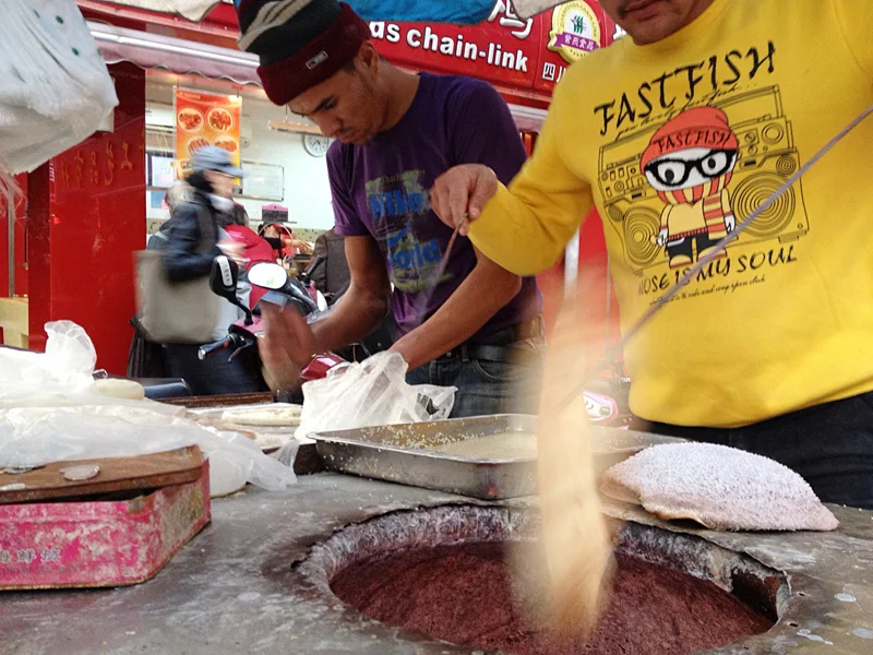 These men from Iran were making Barbri bread -- a common Persian flat bread that is cooked in a hot charcoal oven. The dough is lightly dusted in Sesame seeds then stamped and thrown in the oven to bake. The result is a light, fluffy bread with a slight sweetness and crunch. 