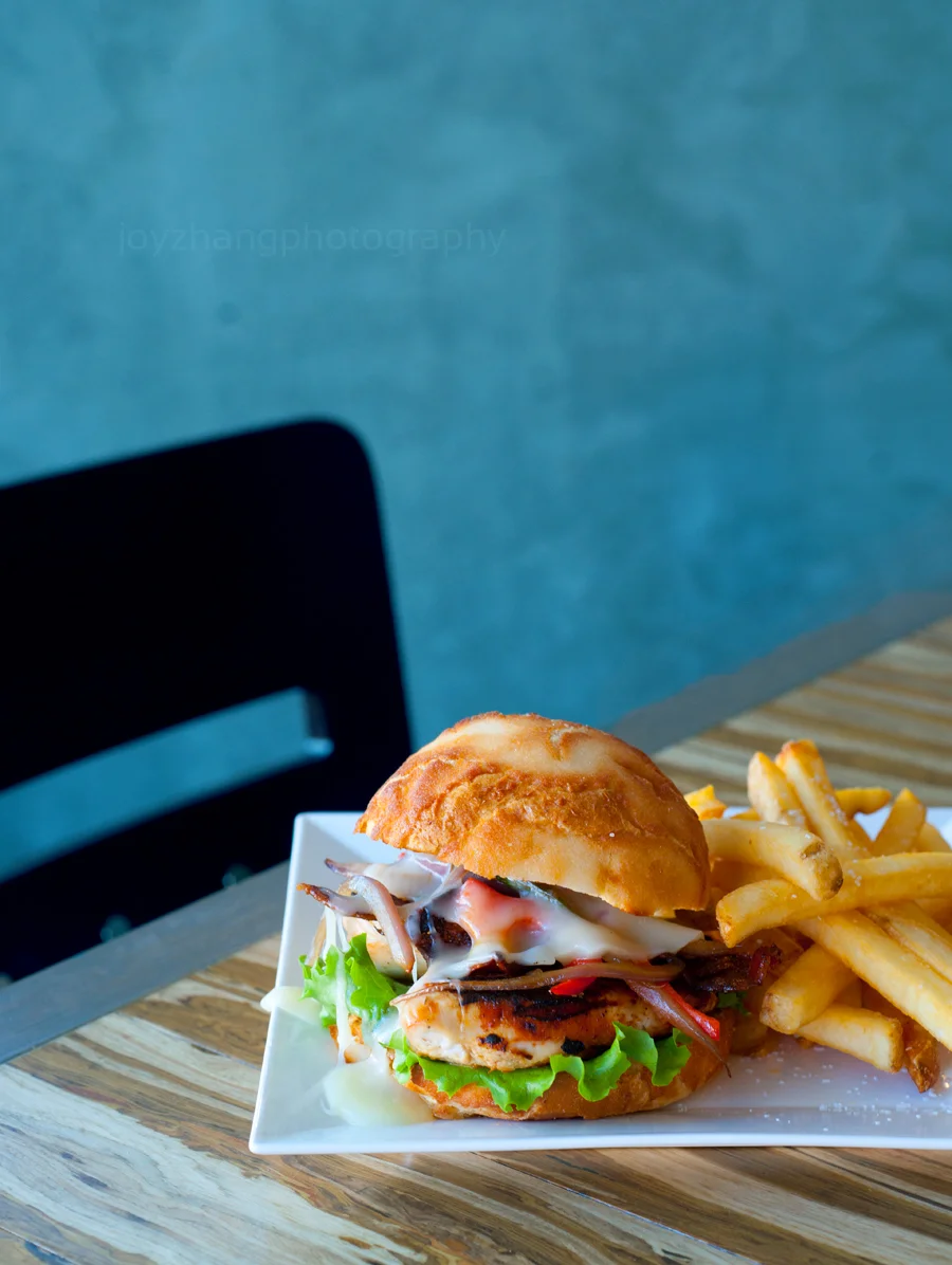 Chipotle Chicken Sandwich with sautéed peppers, queso blanco, bacon, lettuce, tomato, aioli drizzle and criolla served on Amazon crunch bun