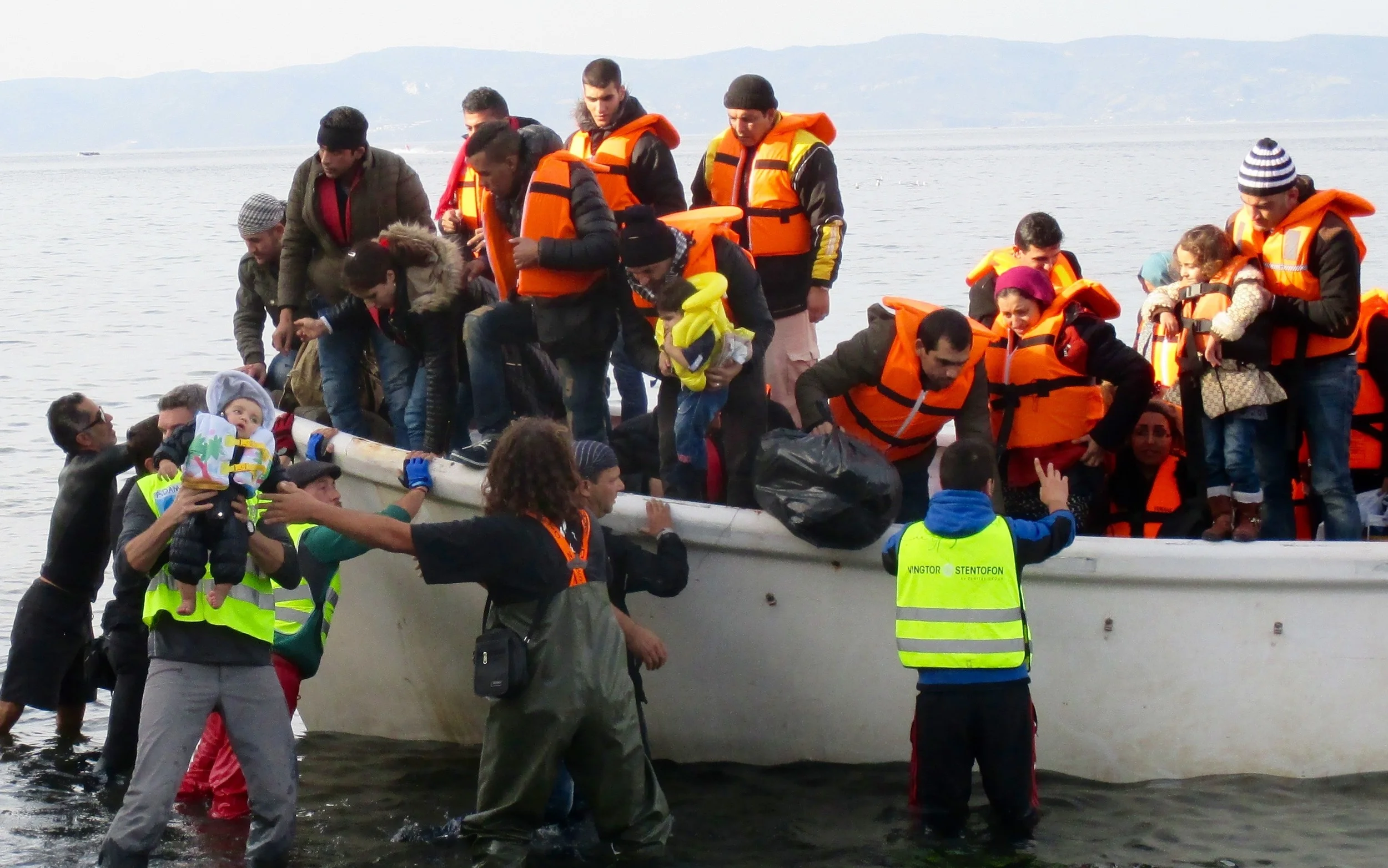 Arriving in a coastguard boat that rescued them from their sinking dinghy, children are offloaded first by a variety of different volunteers organizations acting as first responders on the shore.