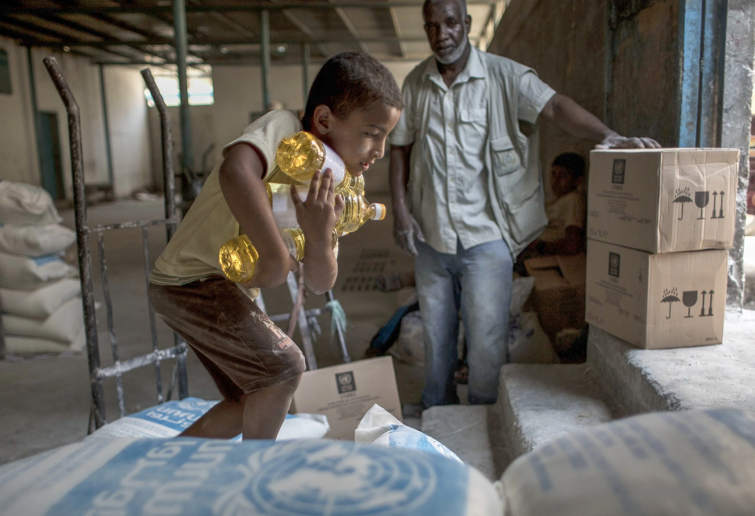 A Palestinian boy carries bottles of oil distributed at UNRWA’s aid distribution center in Rafah in the southern Gaza Strip. (AFP PHOTO / SAID KHATIB)